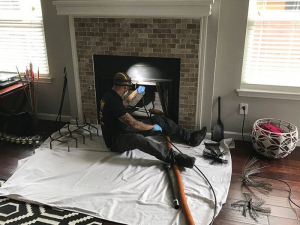 Texas Air Duct Cleaning tech sitting on the ground cleaning a client's chimney.